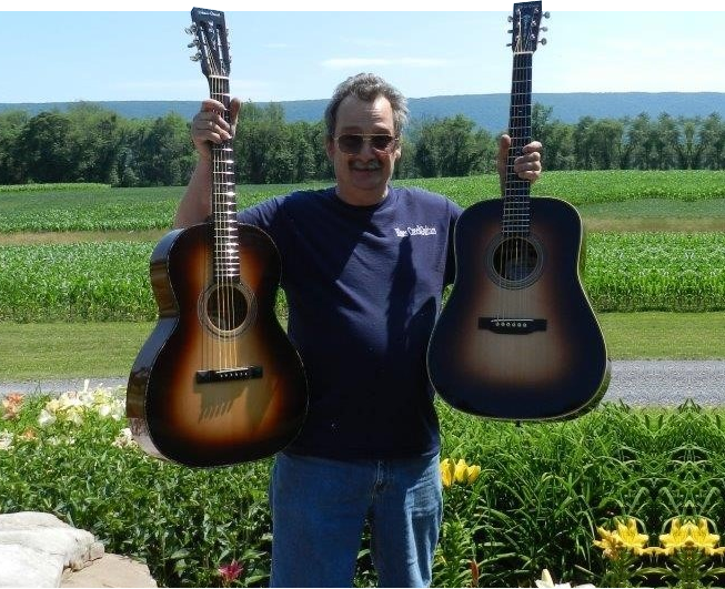 A man holding two guitars